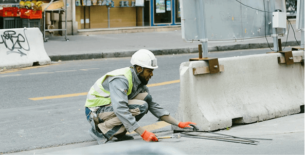 Construction worker inspecting rebar on a street barrier